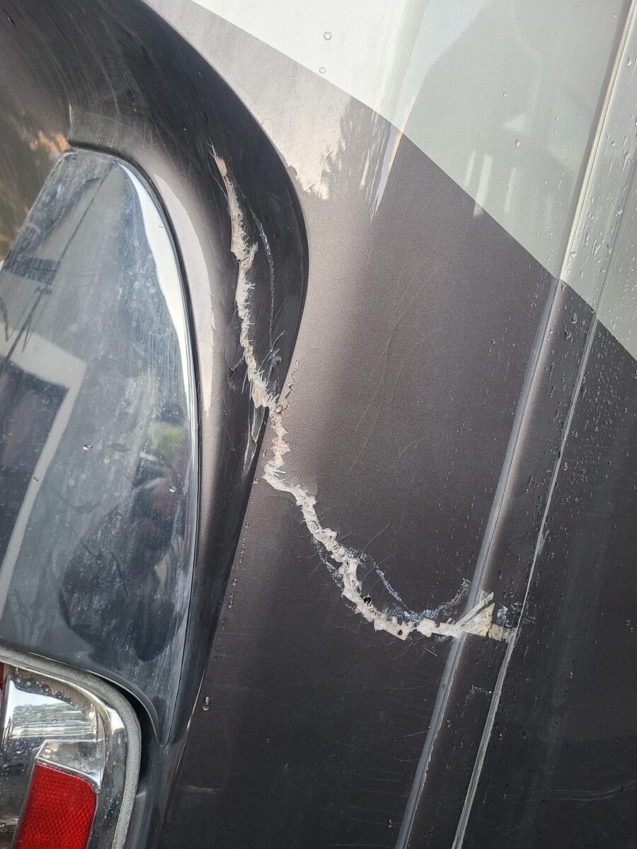 Torn fiberglass on the rear cap of the RV showing the extent of the impact damage
