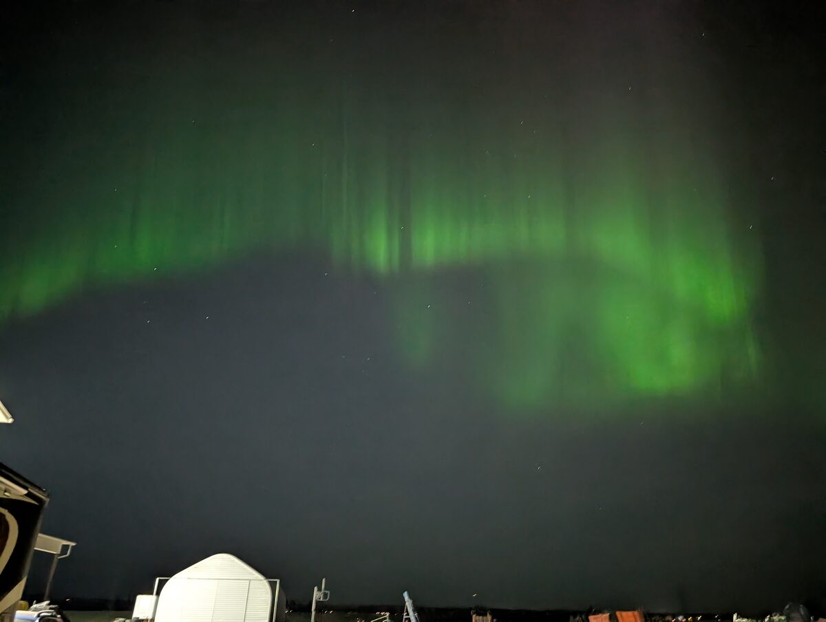 Green aurora borealis dancing above farm buildings in Alberta Canada