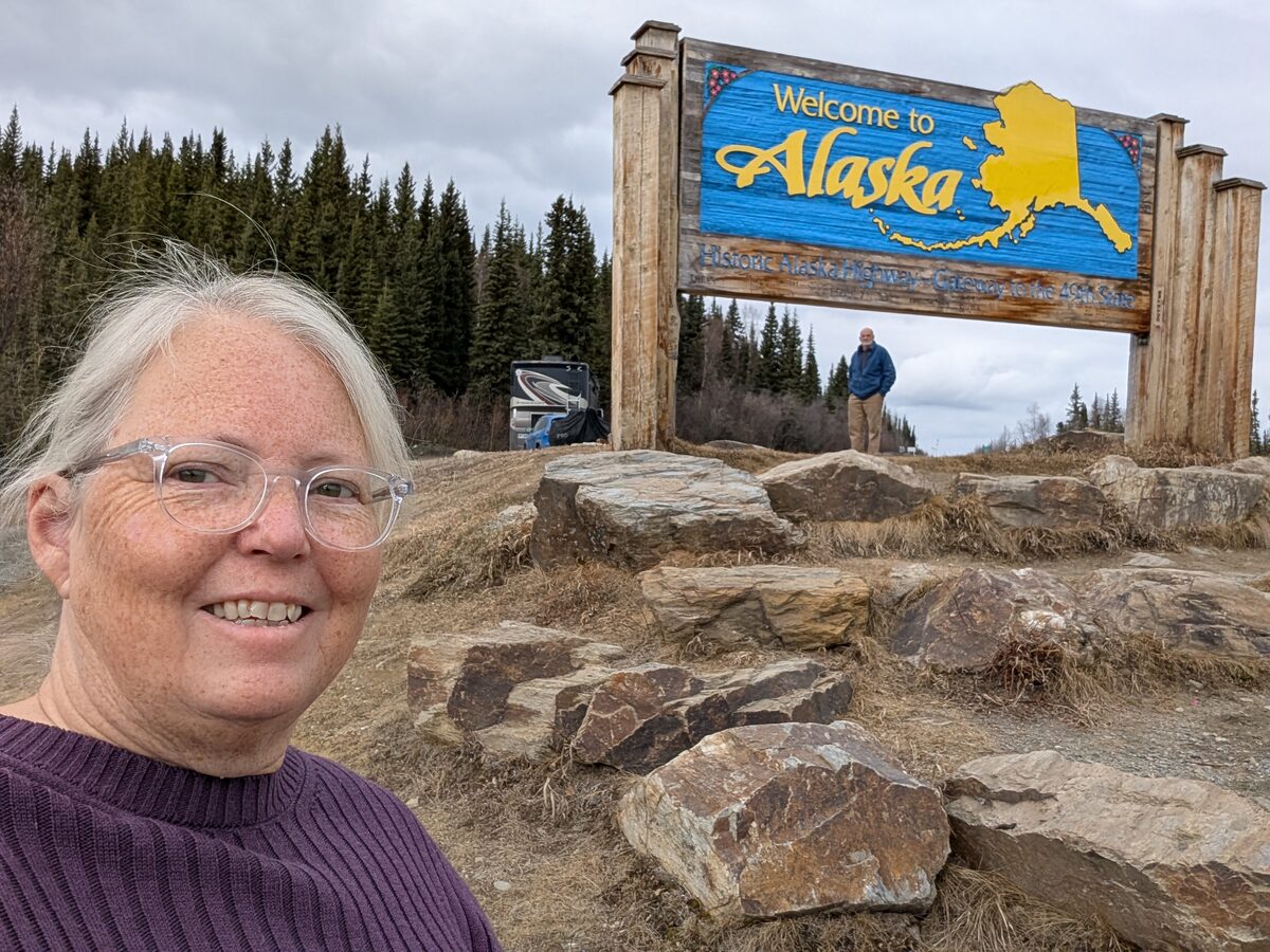 Phyllis selfie at the Welcome to Alaska sign on the Historic Alaska Highway