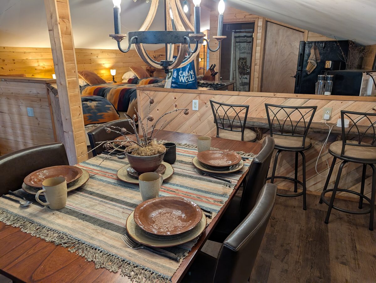Cozy glamping cabin interior at Airbnb in Wrangell-St Elias with rustic wood decor and dining table set for four