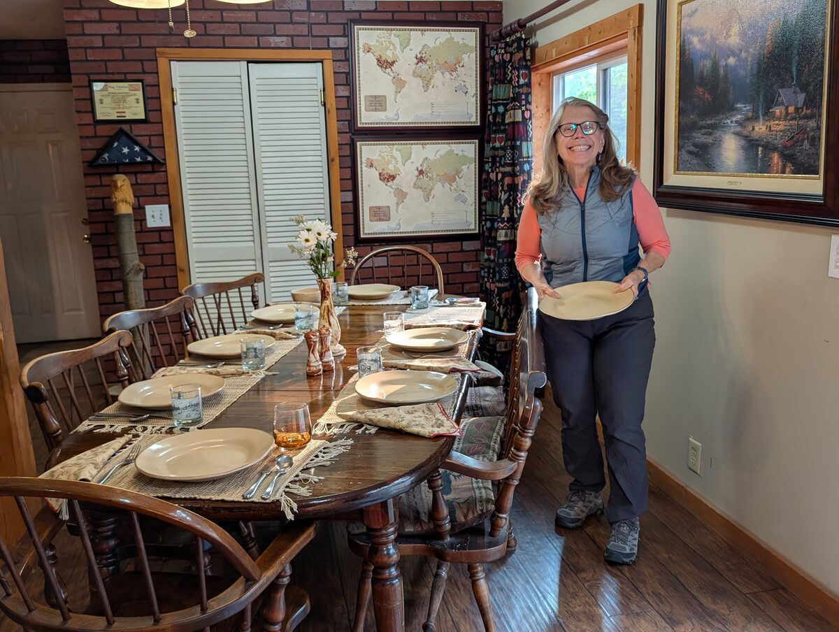 Kathleen smiling while setting the table for breakfast at our VRBO