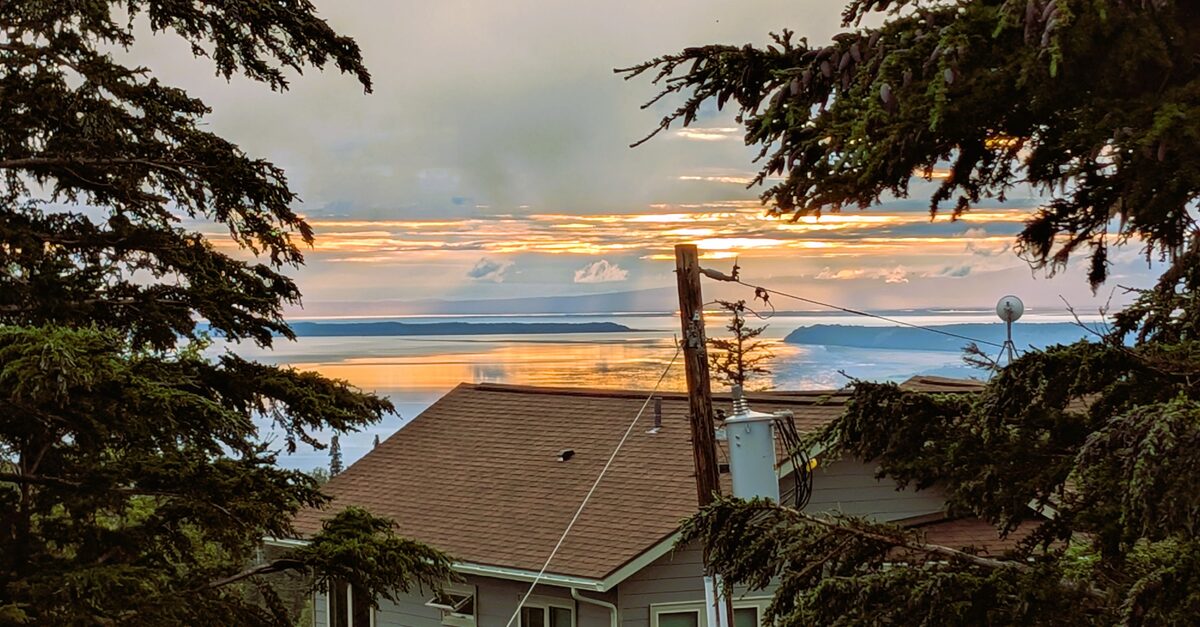 The view from the rental house - Late night Alaska summer sunset over Cook Inlet viewed through spruce trees